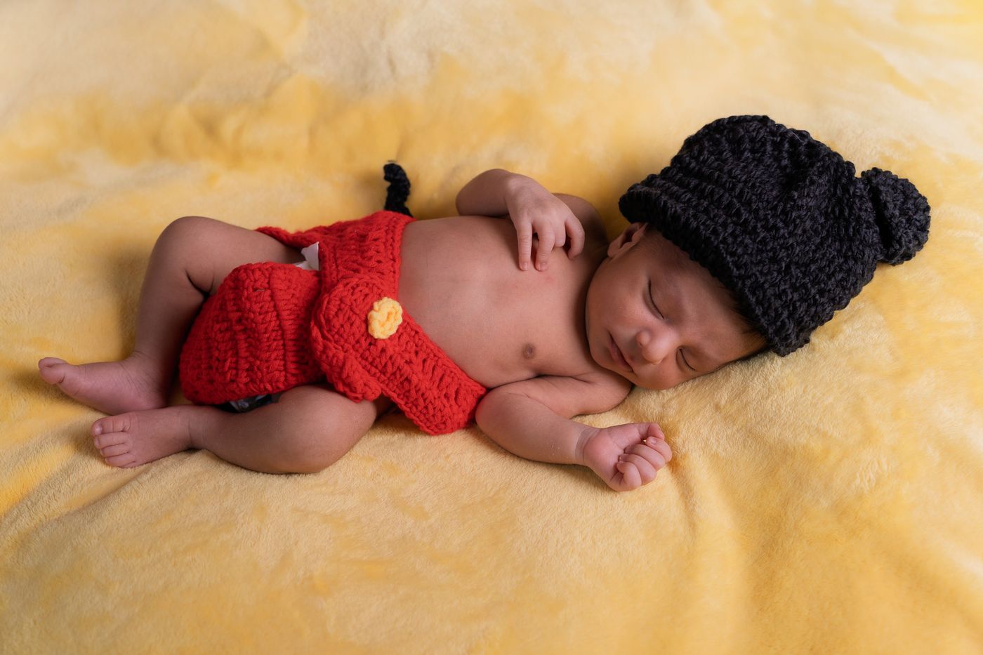 Recién nacido con gorro tejido durmiendo sobre una manta amarilla