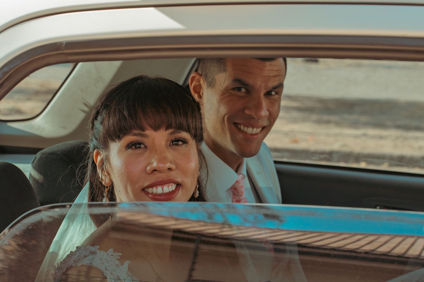 Los novios sonriendo dentro de un auto clasico celeste