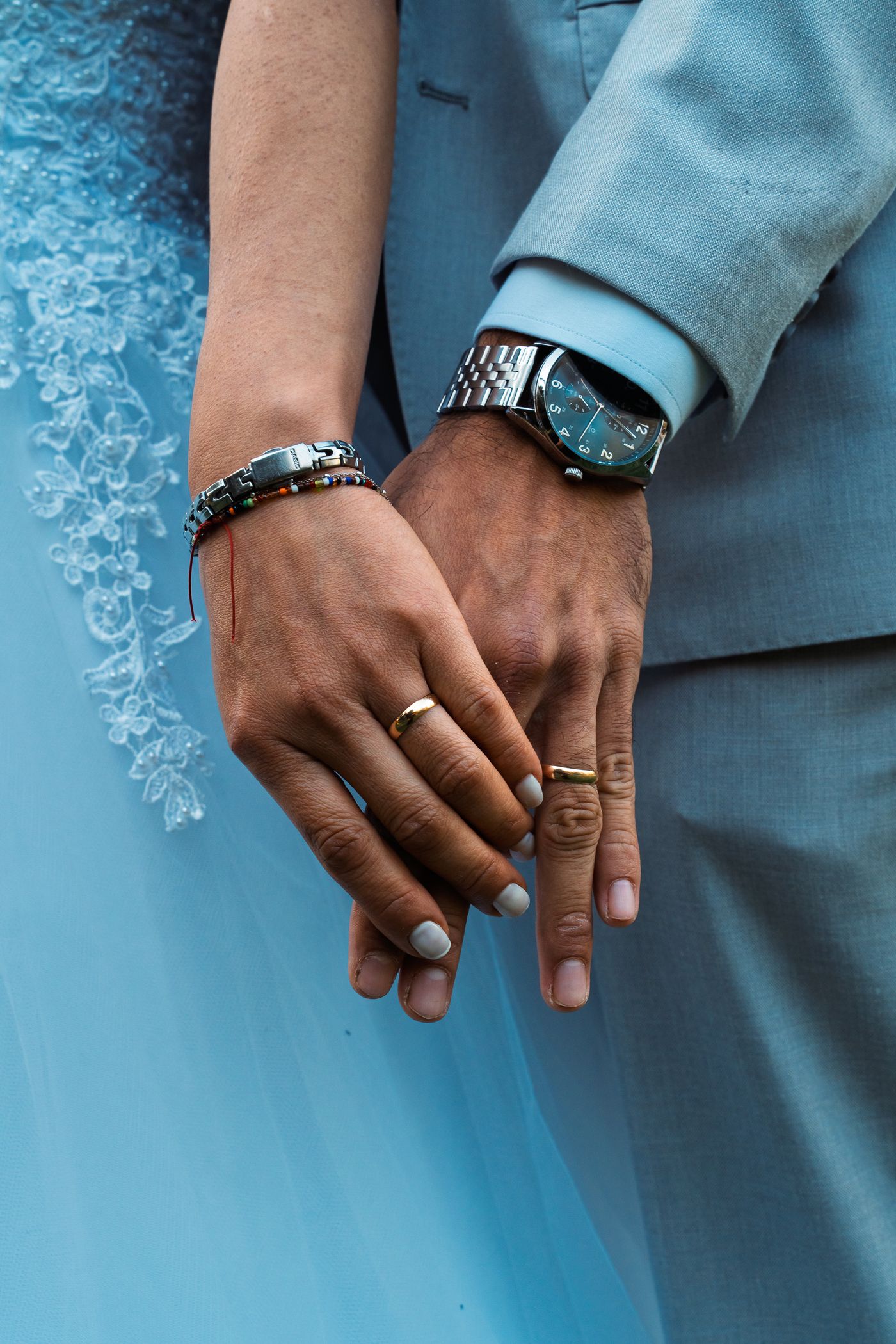 Manos de los novios entrelazadas mostrando los anillos de matrimonio