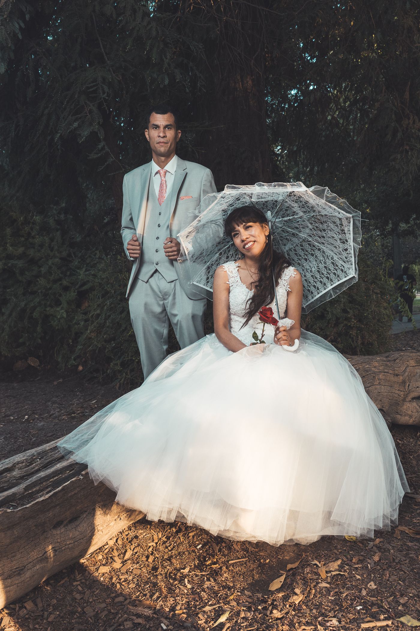Novios posando bajo un paraguas transparente en un día de lluvia