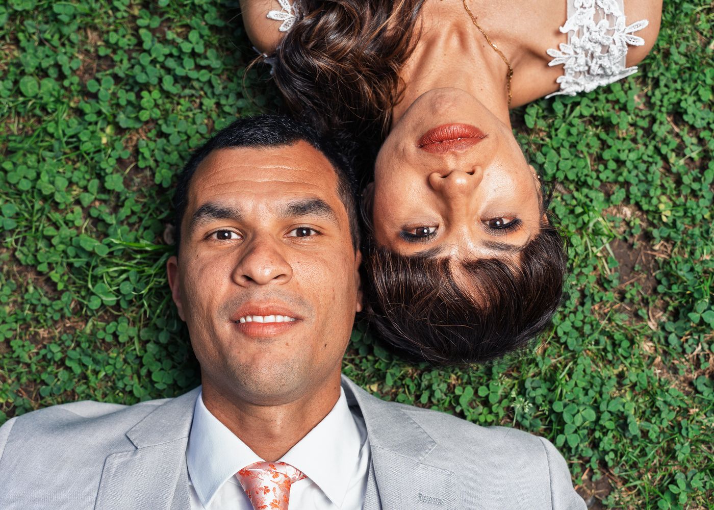 Los novios recostados sobre el pasto en posiciones opuestas, riendo