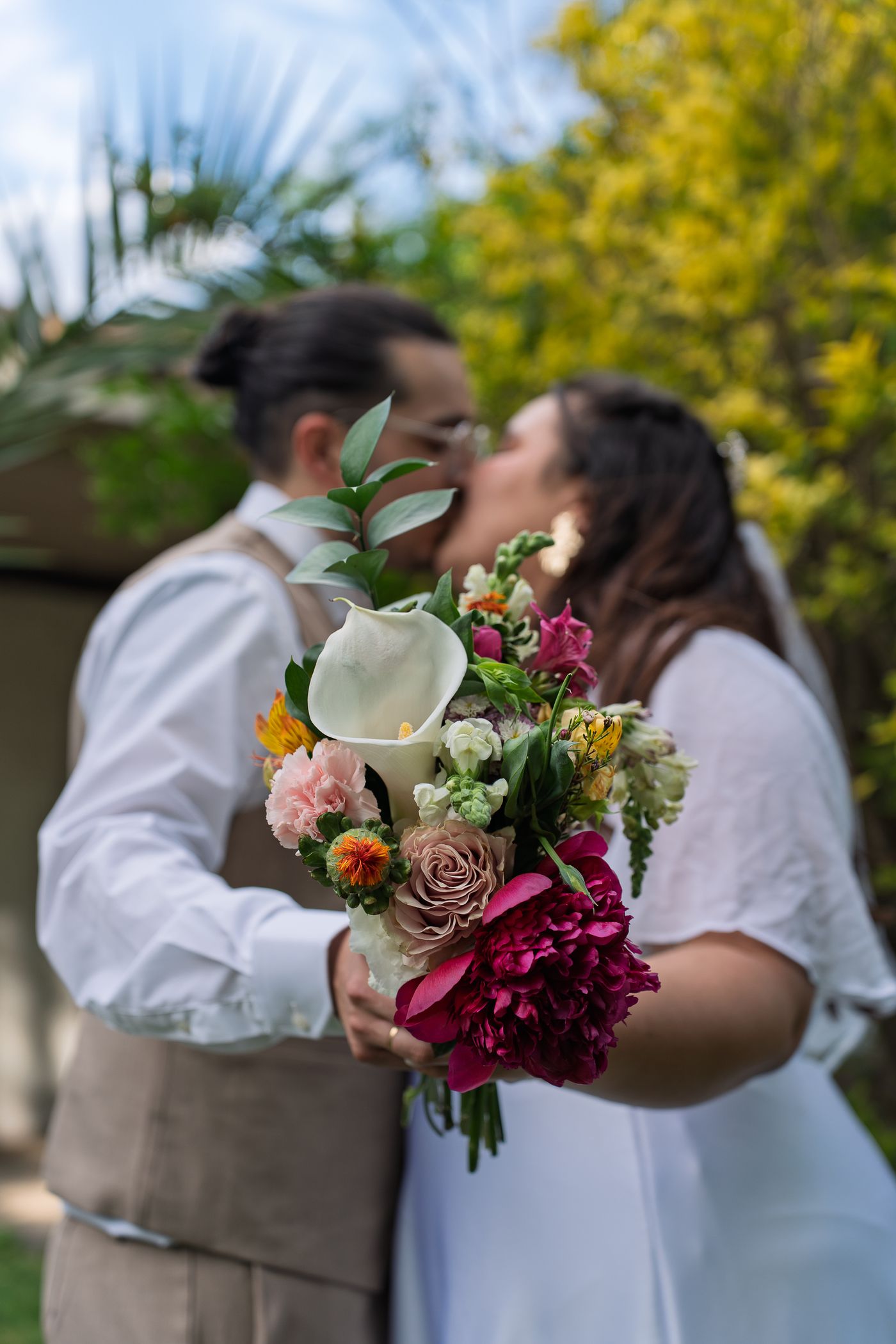 Novia con un ramo de flores rosadas junto al novio