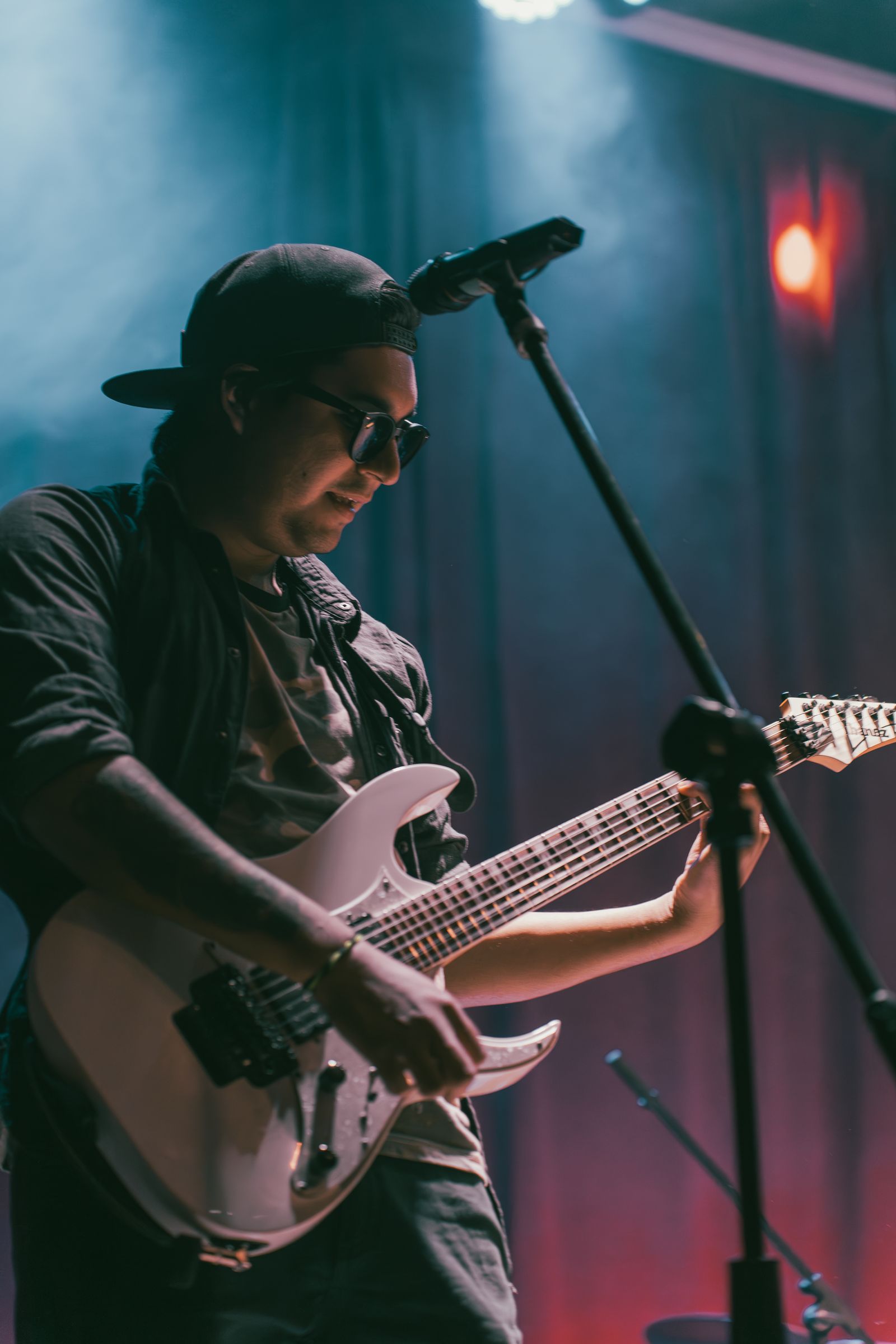 Guitarrista tocando en vivo bajo luces rojas y azules de escenario
