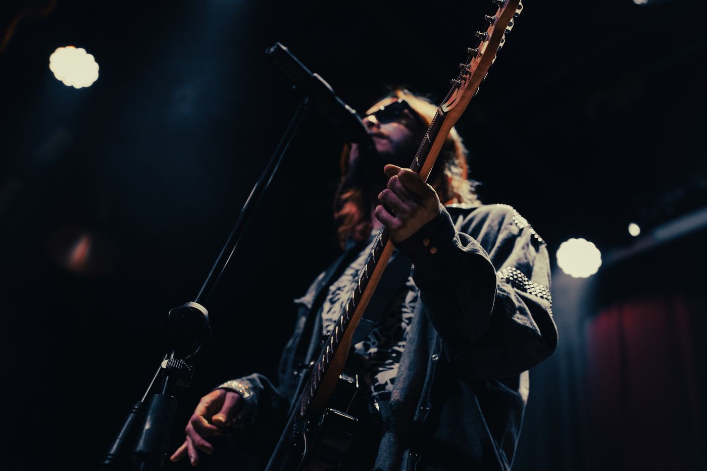 Vocalista cantando con la guitarra en alto durante un show en vivo