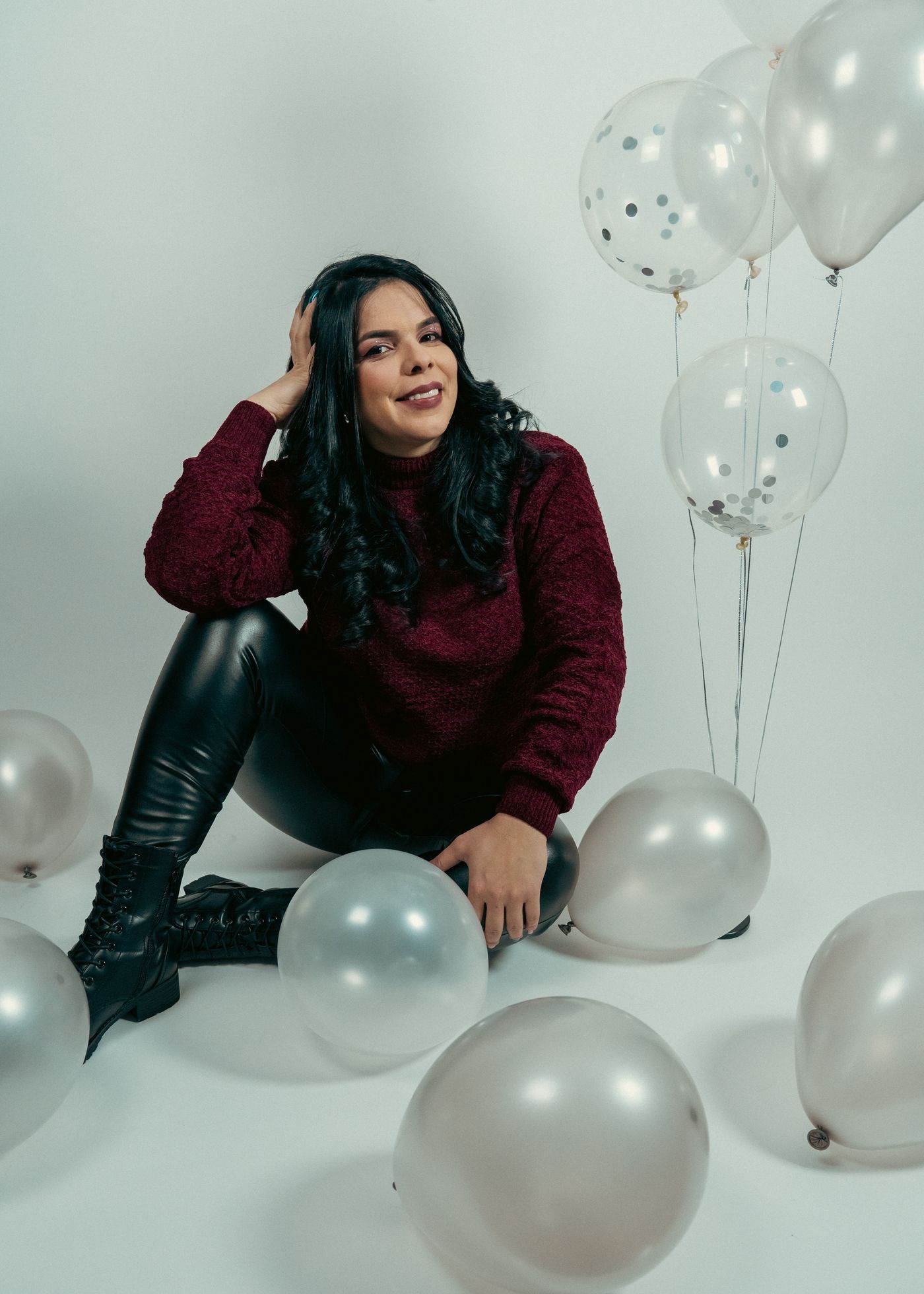 Mujer sentada entre globos plateados en una sesión de cumpleaños