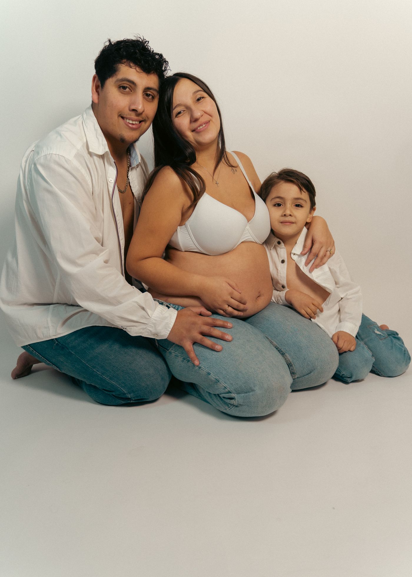 Familia completa posando en una sesión de embarazo en estudio
