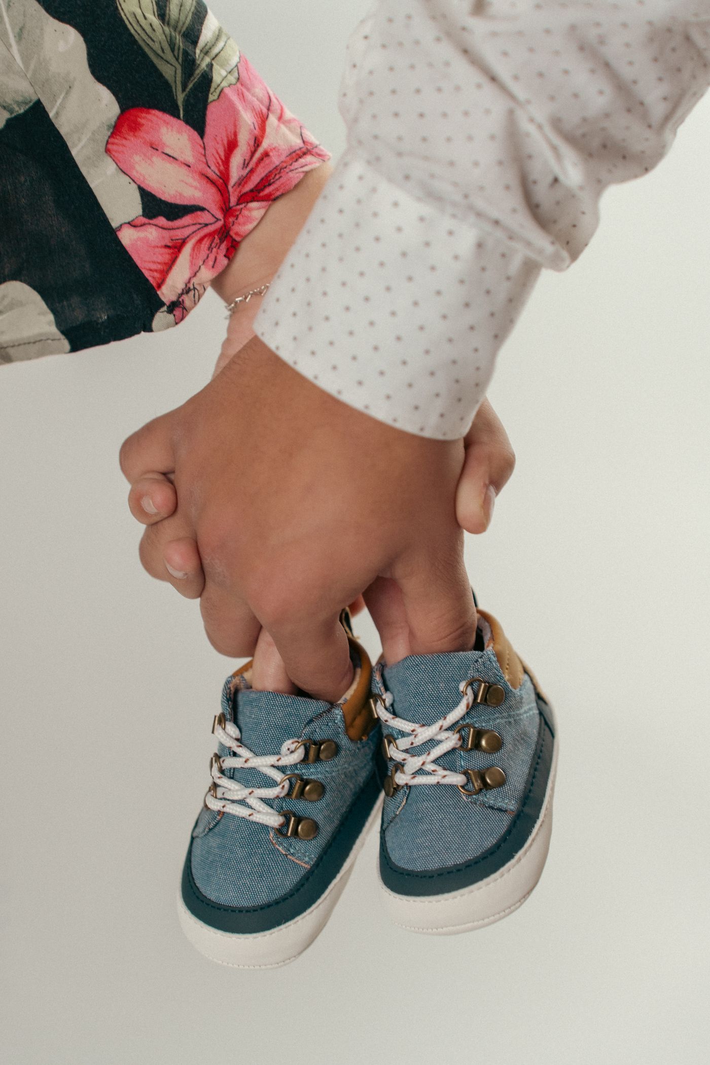 Manos de una pareja sosteniendo unos zapatitos de bebé