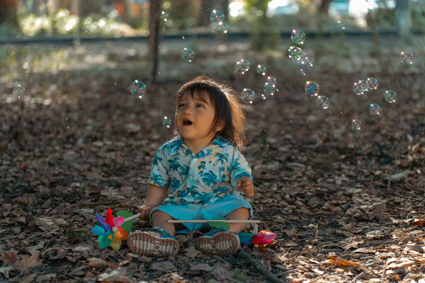 Niño pequeño jugando con burbujas de jabon en un parque