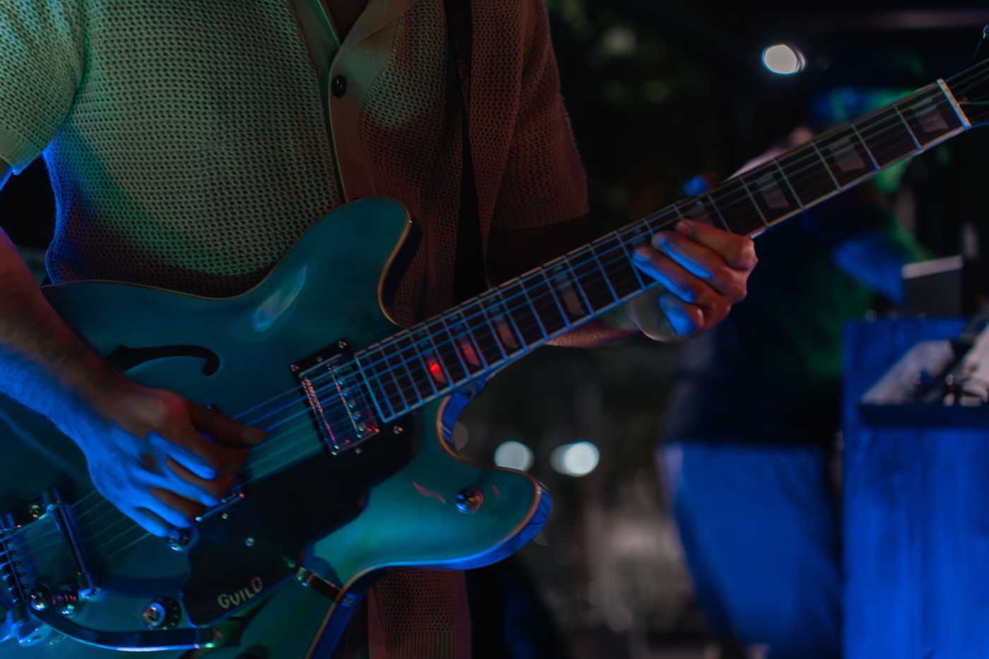 Guitarra electrica celeste iluminada con luz azul durante una grabación