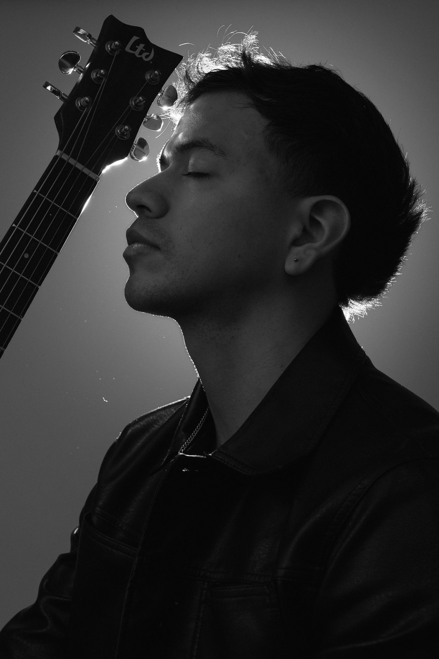Musico con guitarra iluminado a contraluz en estudio