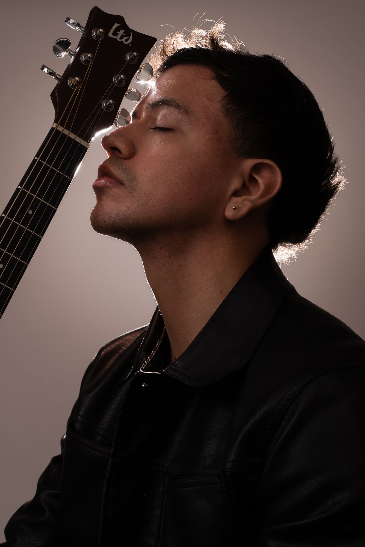 Retrato de perfil de un músico apoyado en su guitarra