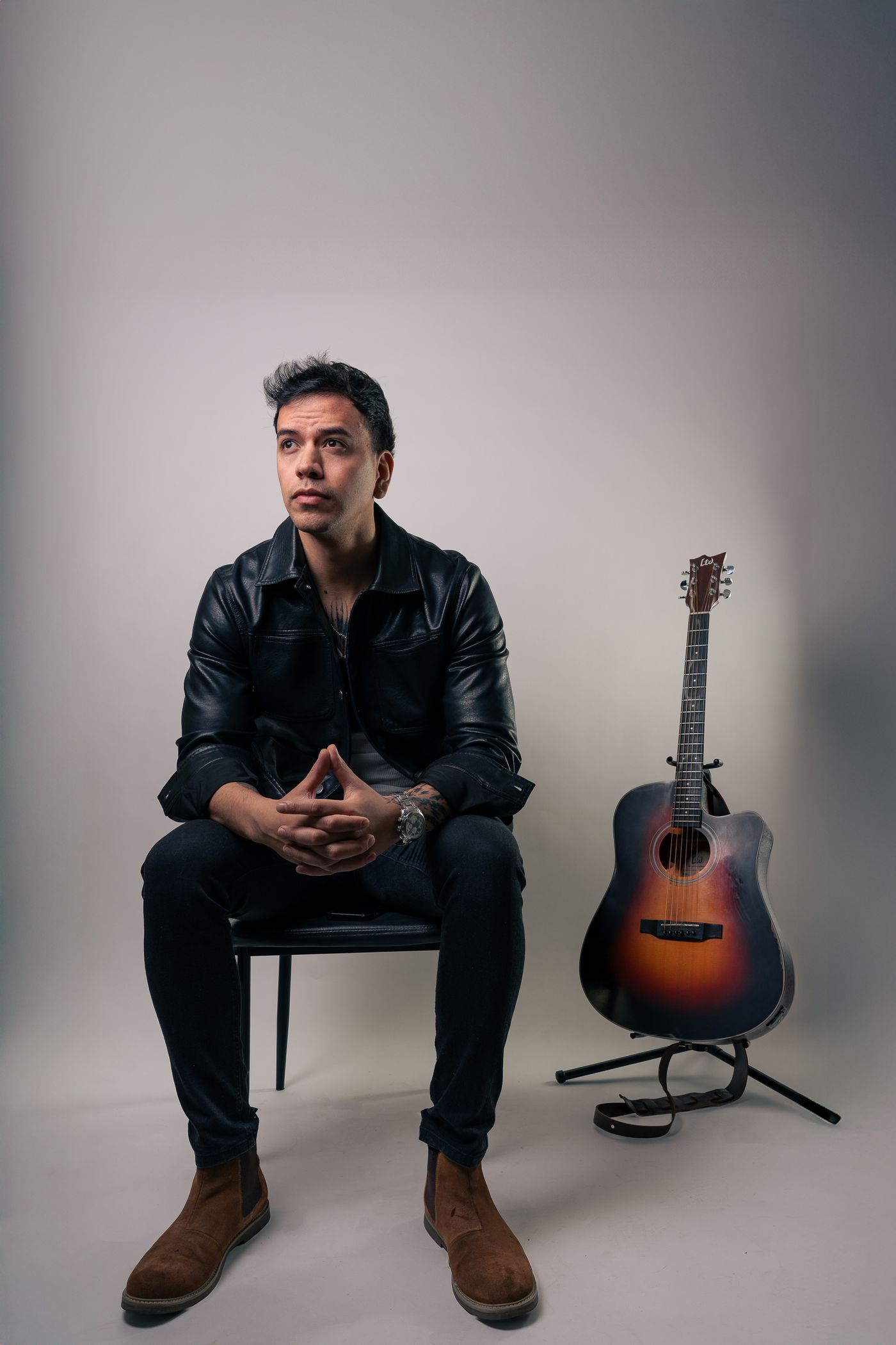 Musico sentado junto a su guitarra acustica en estudio